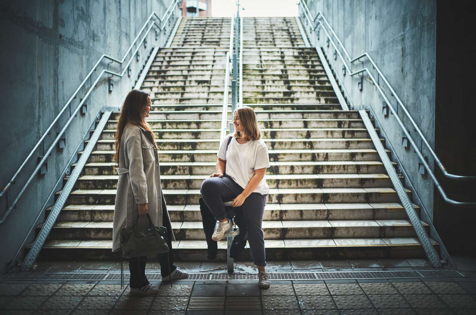 To piger der taler sammen for foden af en trappe